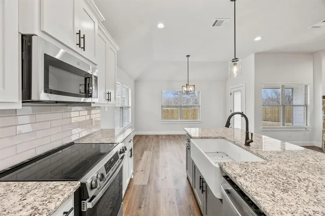a kitchen with stainless steel appliances granite countertop a stove a sink and a wooden floor