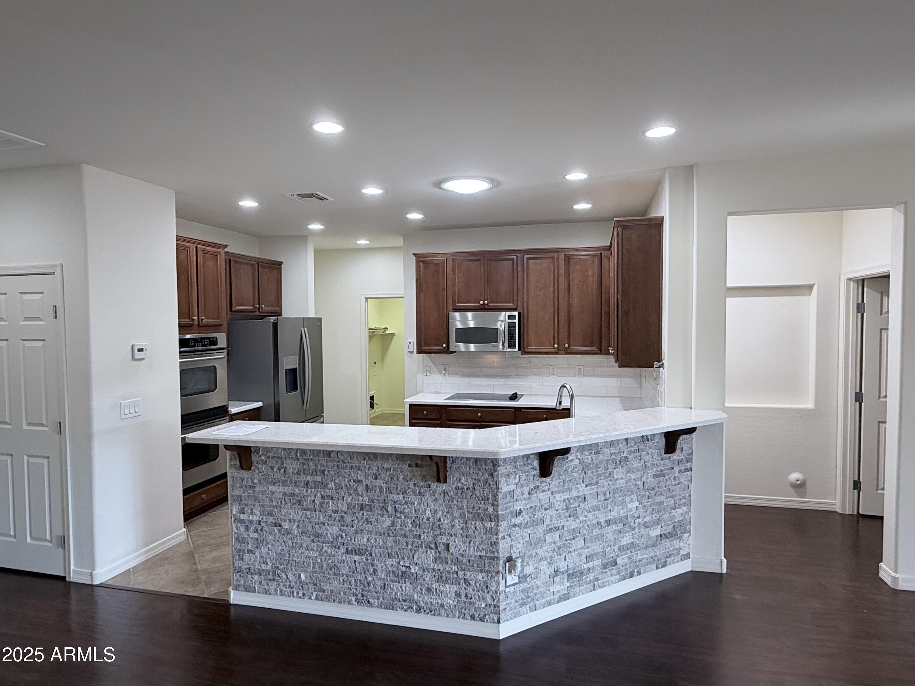 16549 West Rowel Road Surprise, AZ 85387 - Photo 11 of 23 a kitchen with kitchen island granite countertop a refrigerator oven a sink and cabinets
