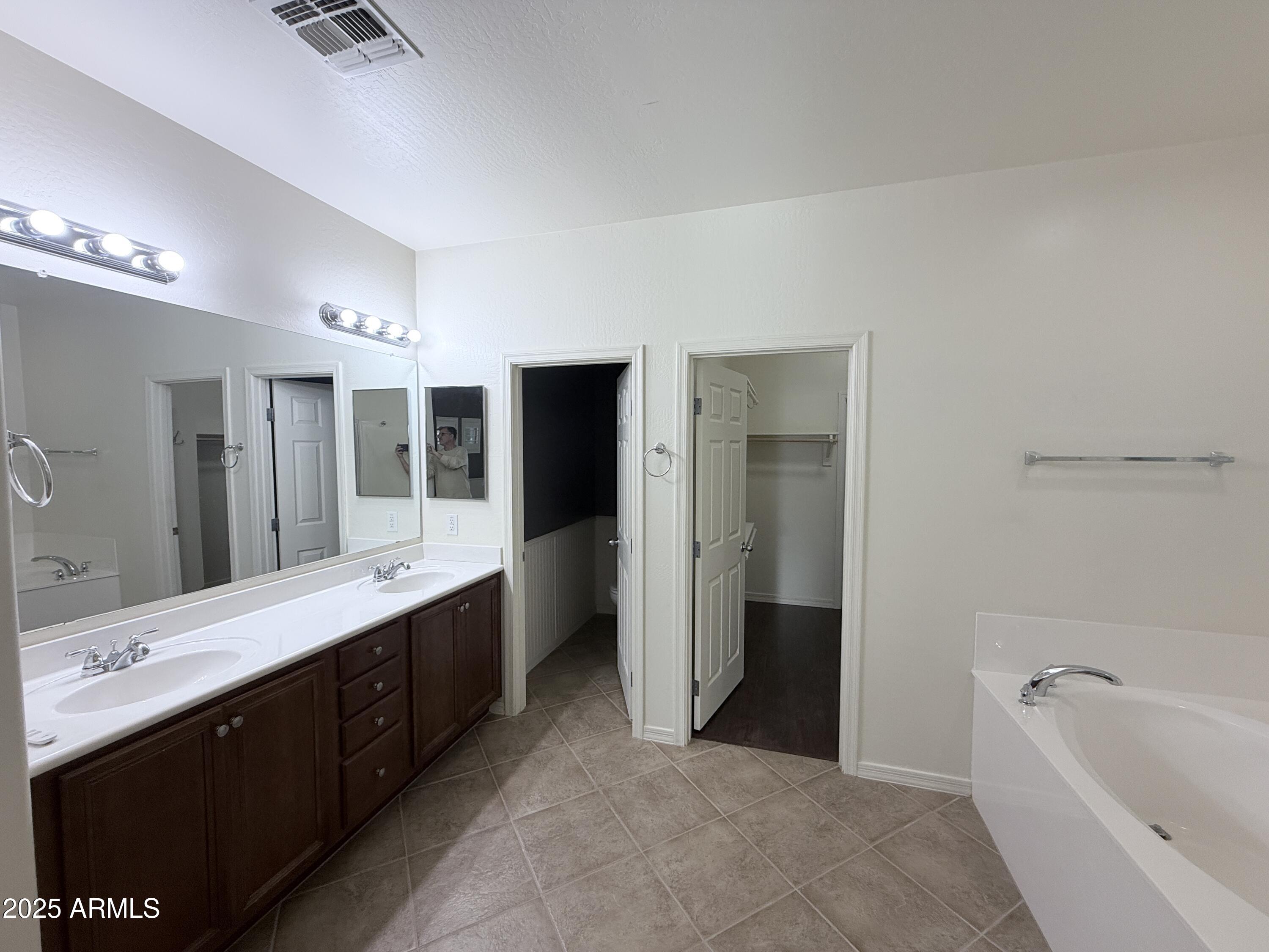 16549 West Rowel Road Surprise, AZ 85387 - Photo 15 of 23 a large bathroom with a double vanity sink a large mirror and a bathtub