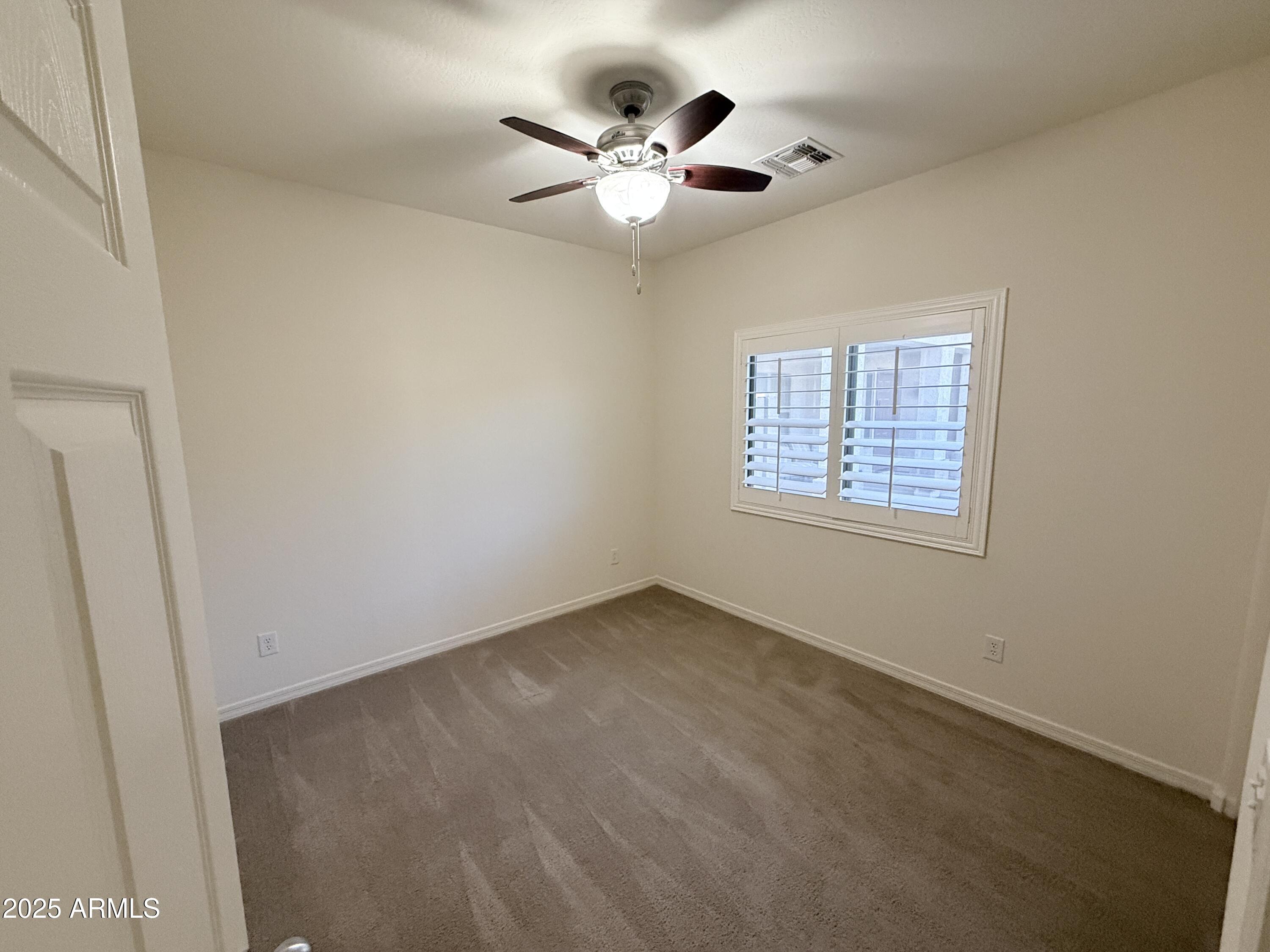16549 West Rowel Road Surprise, AZ 85387 - Photo 4 of 23 an empty room with ceiling fan and windows
