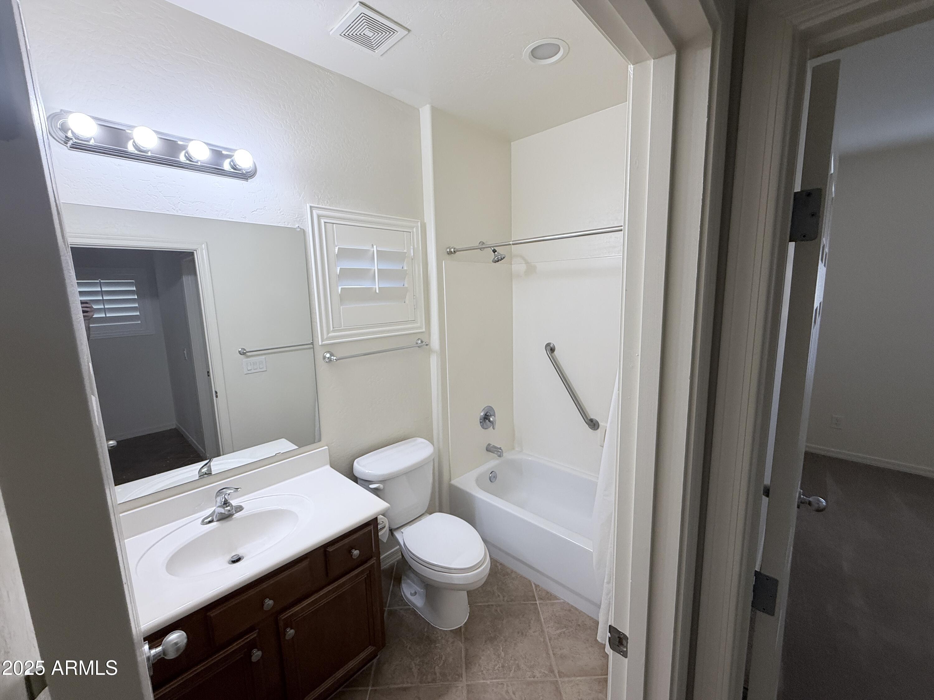 16549 West Rowel Road Surprise, AZ 85387 - Photo 5 of 23 a bathroom with a granite countertop sink toilet a large mirror a shower and vanity