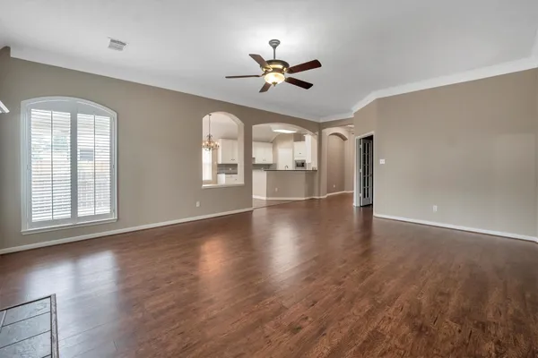 a kitchen with stainless steel appliances granite countertop a refrigerator a sink and white cabinets with wooden floor