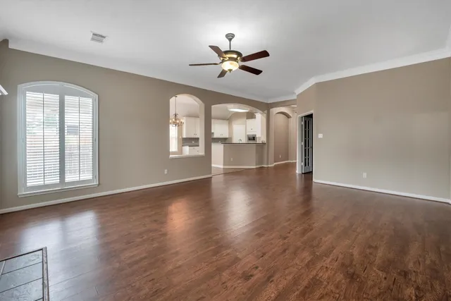 a kitchen with stainless steel appliances granite countertop a refrigerator a sink and white cabinets with wooden floor