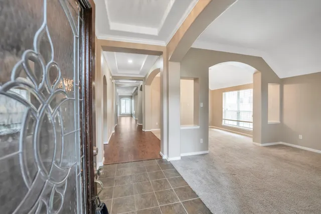 a view of an empty room with chandelier fan and wooden floor