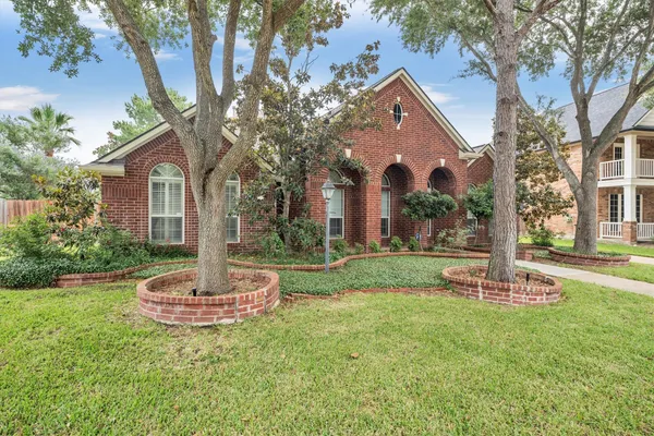a view of a white house next to a yard and large trees