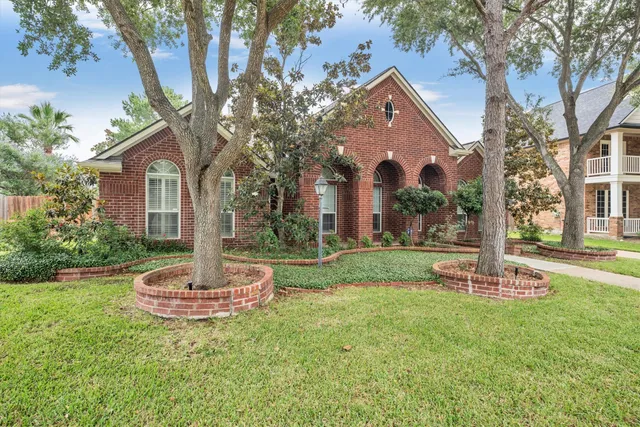 a view of a white house next to a yard and large trees