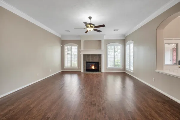 an empty room with wooden floor fireplace and windows