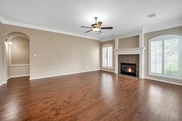 an empty room with wooden floor fireplace and windows