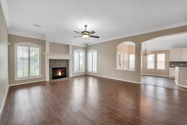 a view of a livingroom with wooden floor a ceiling fan and windows