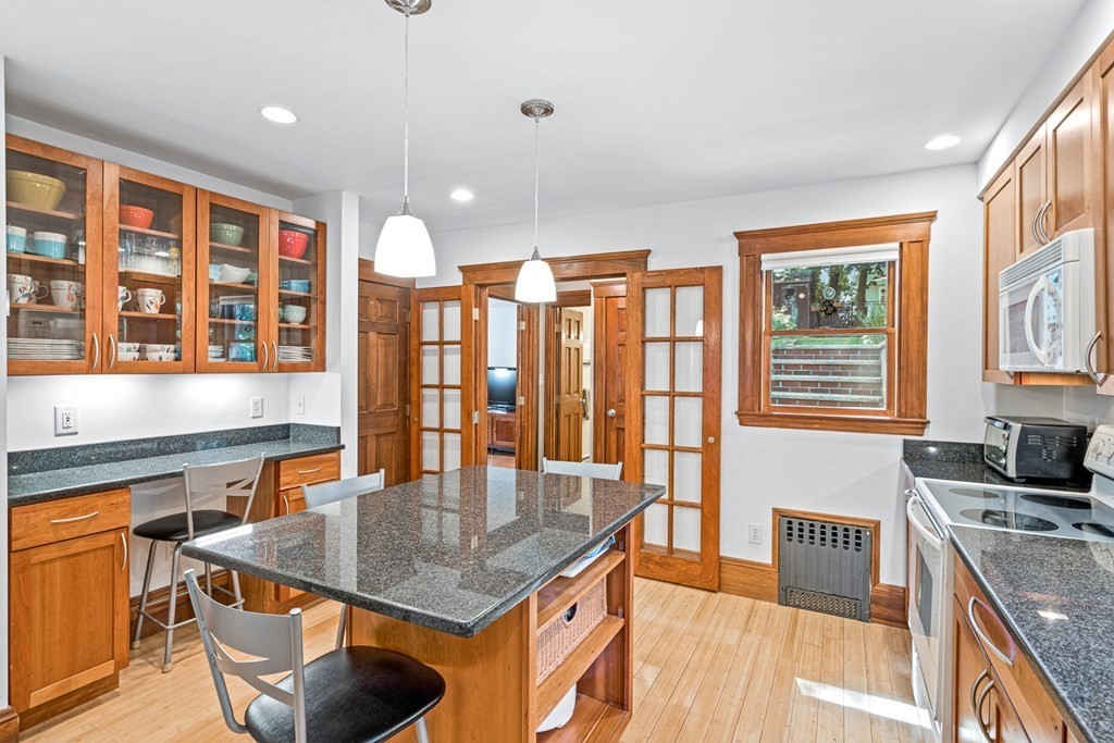 11 Ronald Road Arlington, MA 02474 - Photo 13 of 42 a kitchen with stainless steel appliances granite countertop a stove a sink dishwasher and a dining table with wooden floor