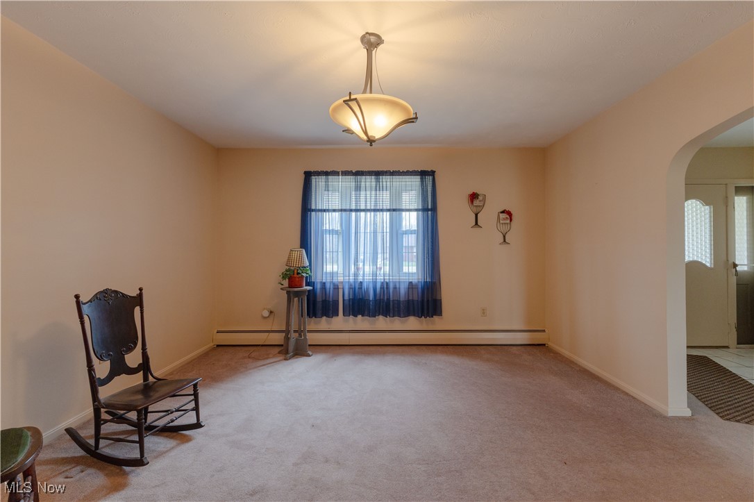 1639 South Ridge Road West Ashtabula, OH 44004 - Photo 12 of 44 Unfurnished room featuring arched walkways, a baseboard heating unit, baseboards, and carpet