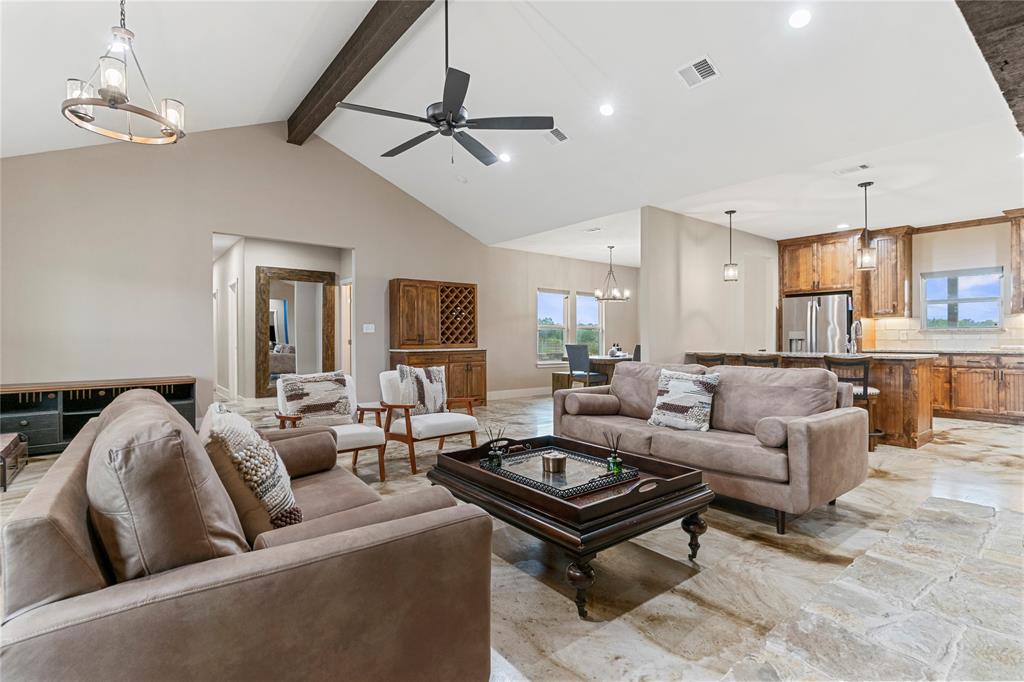 139 Kriston Lane Springtown, TX 76082 - Photo 7 of 39 Expansive living area featuring vaulted ceilings with exposed beam, a ceiling fan, and a chandelier