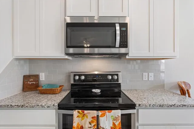 a kitchen with granite countertop a stove and a microwave