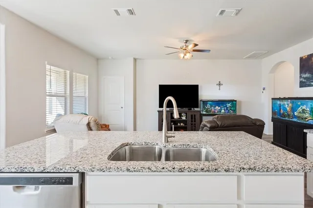a kitchen with kitchen island granite countertop a sink a counter top space and living room view