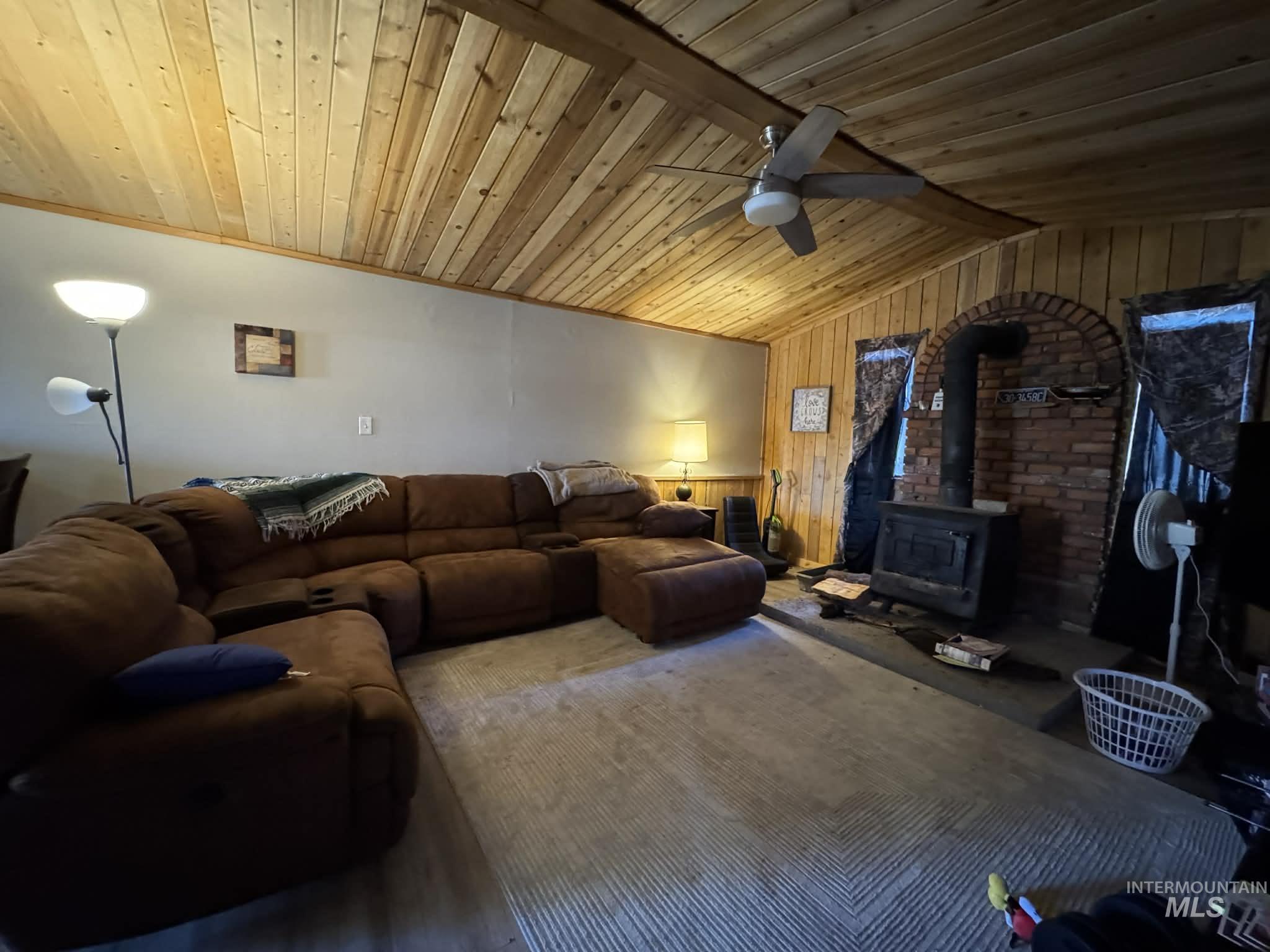 40238 Sr 129 Anatone, WA 99401 - Photo 2 of 13 Living area with a wood stove, a ceiling fan, wooden walls, and a wood ceiling with exposed beams