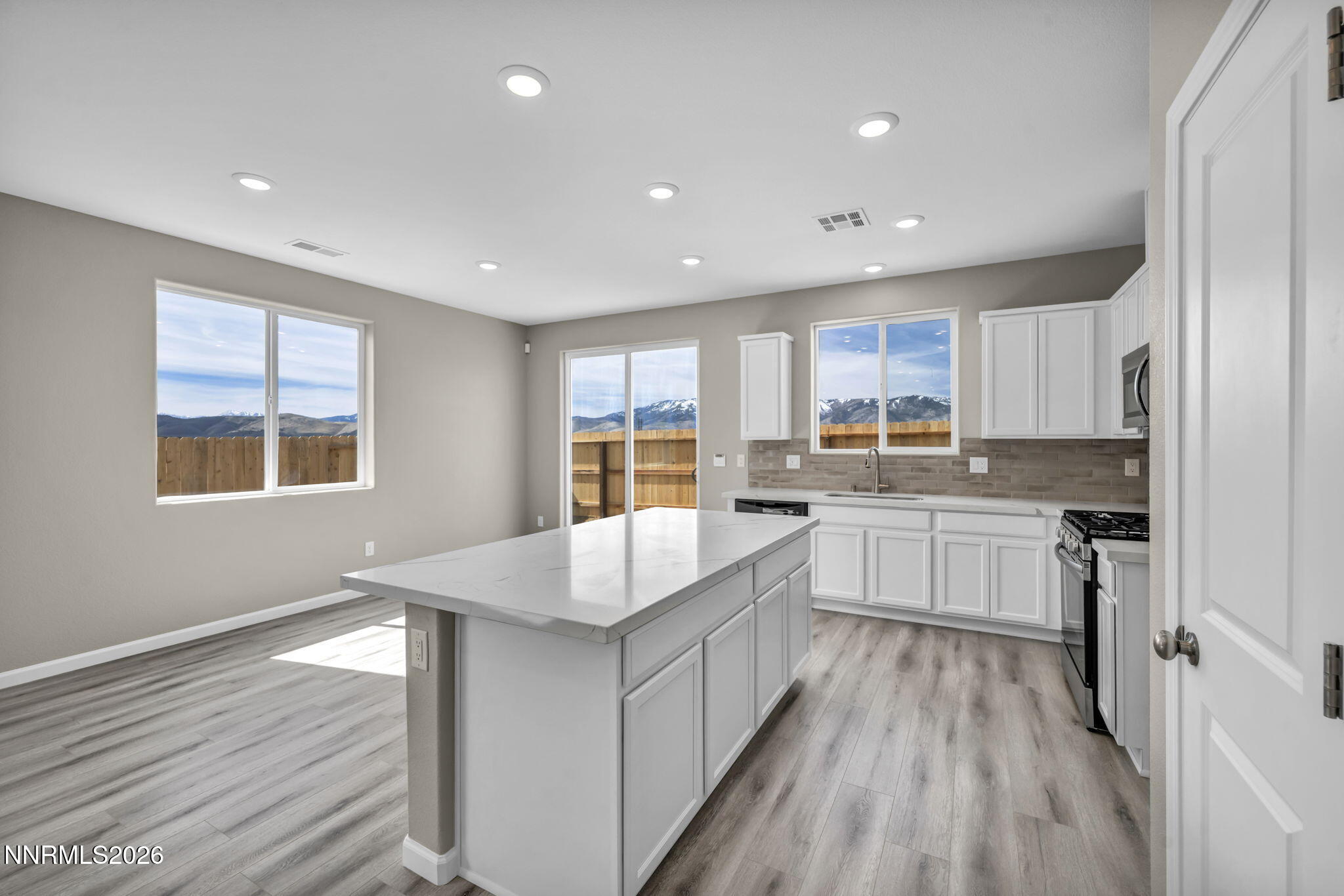 6668 Morgan Mill Road, Unit HOMESITE 15 Carson City, NV 89701 - Photo 3 of 25 a large white kitchen with kitchen island wooden floors granite counter tops and a window