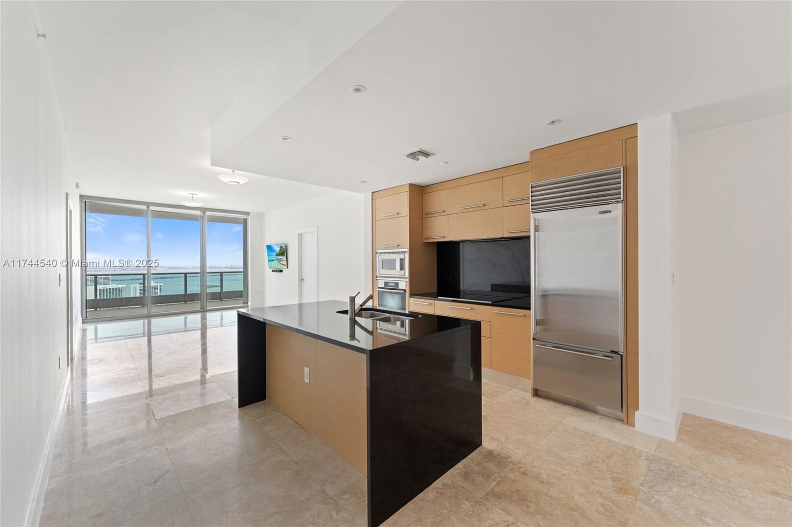 a living room with stainless steel appliances kitchen island granite countertop a refrigerator and a sink