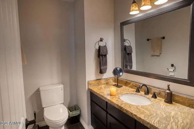 a bathroom with a granite countertop toilet sink and mirror