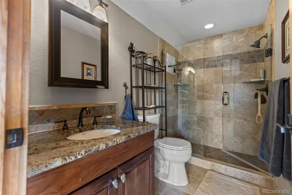 a bathroom with a granite countertop sink toilet and shower