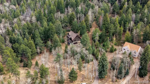 an aerial view of residential house with outdoor space and trees all around