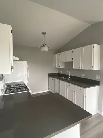 a kitchen with granite countertop a sink a stove and cabinets