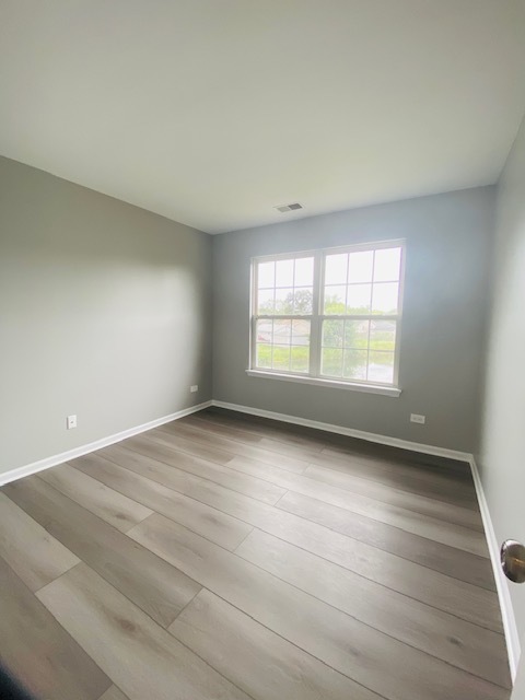 1127 North Red Oak Circle, Unit 4 Round Lake Beach, IL 60073 - Photo 27 of 31 an empty room with wooden floor and windows