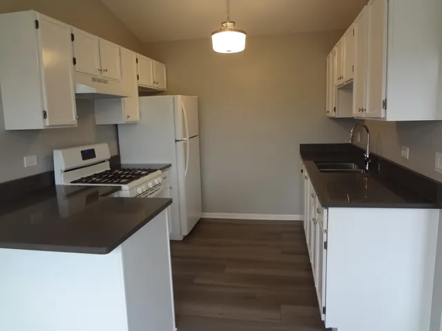 a kitchen with granite countertop a sink a stove and refrigerator