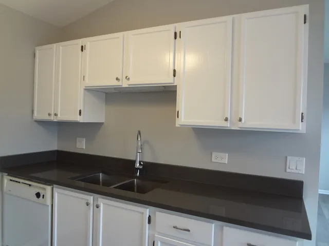 a kitchen with granite countertop white cabinets and a sink