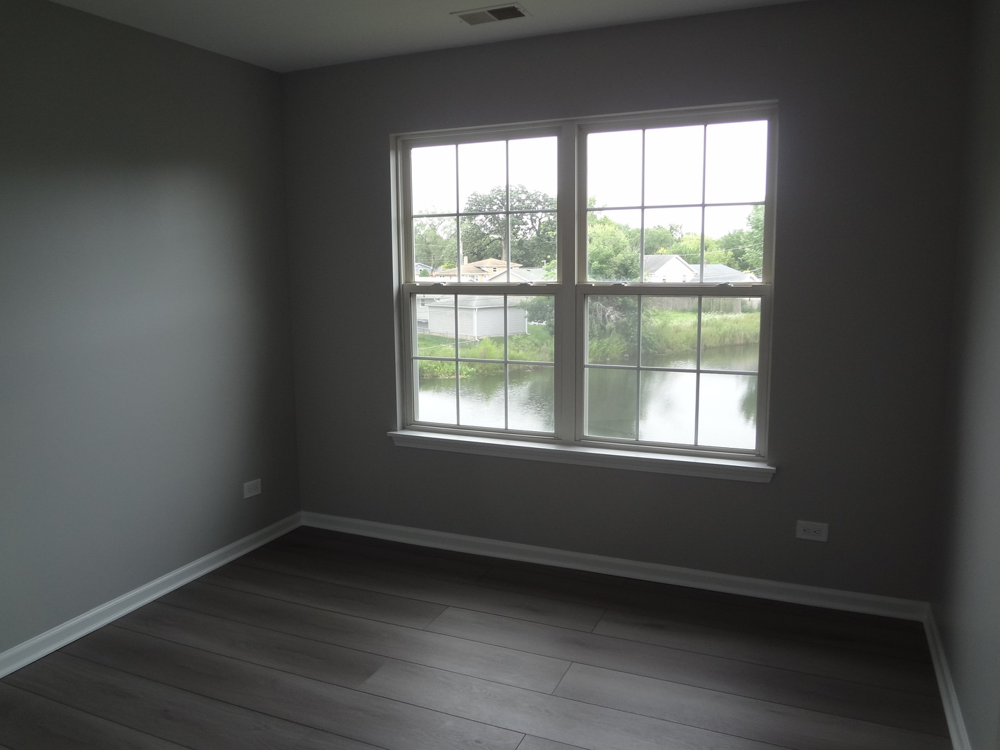 1127 North Red Oak Circle, Unit 4 Round Lake Beach, IL 60073 - Photo 10 of 31 a view of an empty room with wooden floor and a window