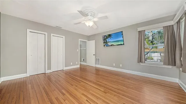 a view of an empty room with wooden floor and a window