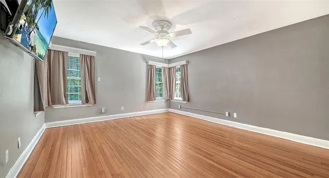 a view of an empty room with wooden floor and a window