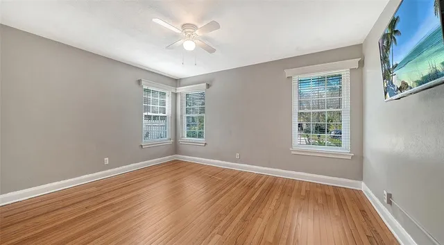 a view of an empty room with wooden floor and a window