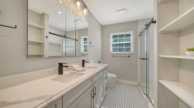 a bathroom with a sink a toilet a mirror and shower