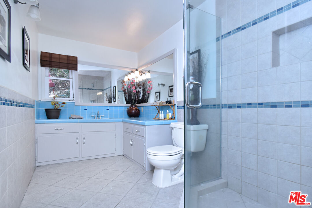 3833 Woodcliff Road Sherman Oaks, CA 91403 - Photo 29 of 52 a spacious bathroom with a granite countertop toilet sink and mirror