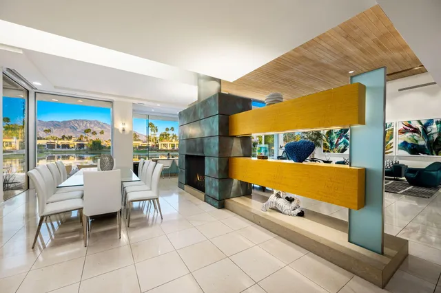 a large white kitchen with a white stove top oven a sink dishwasher a dining table and chairs with wooden floor