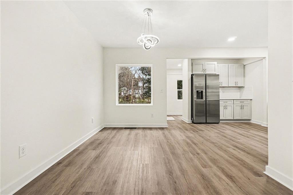 1684 Kenmore Street Southwest Atlanta, GA 30311 - Photo 17 of 30 an empty room with wooden floor kitchen view and windows