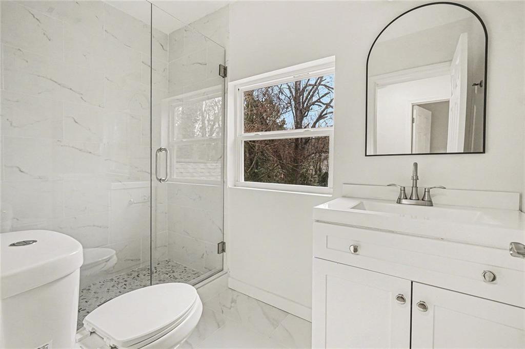 1684 Kenmore Street Southwest Atlanta, GA 30311 - Photo 21 of 30 a bathroom with a toilet a sink a mirror a vanity and shower