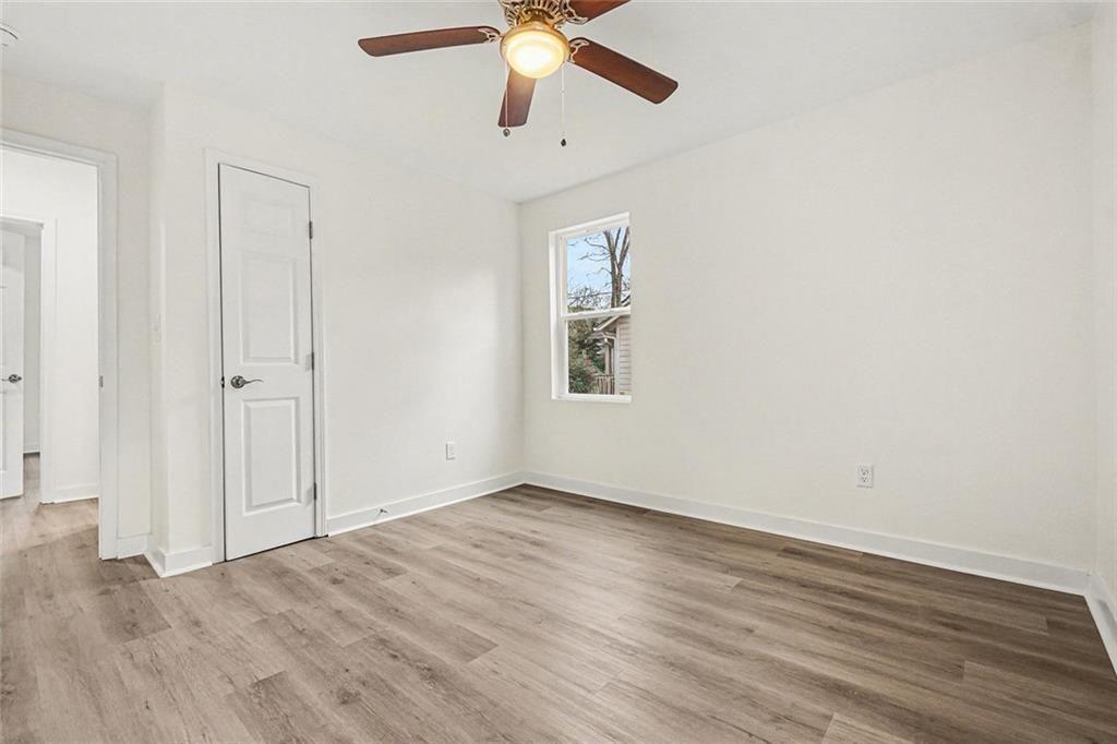 1684 Kenmore Street Southwest Atlanta, GA 30311 - Photo 27 of 30 an empty room with wooden floor ceiling fan and windows