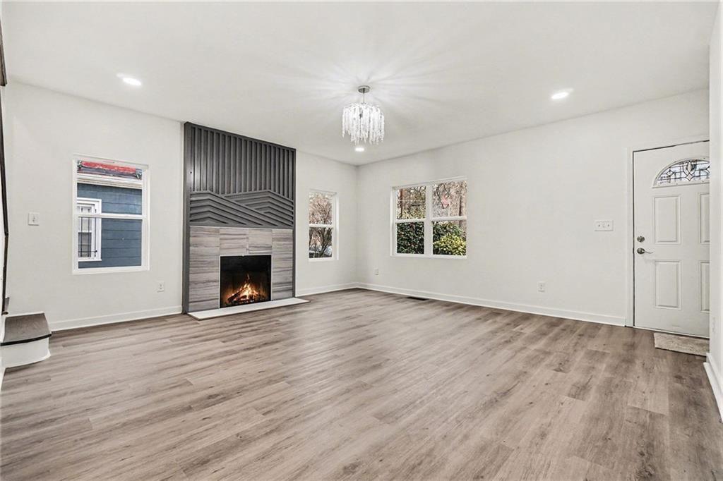 1684 Kenmore Street Southwest Atlanta, GA 30311 - Photo 7 of 30 an empty room with wooden floor fireplace and windows