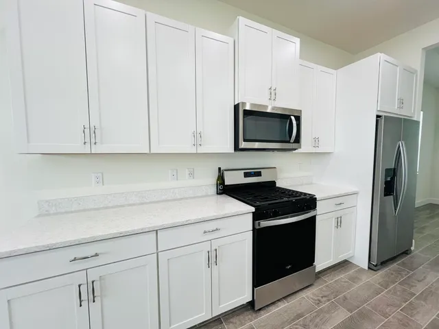 a kitchen with granite countertop white cabinets and stainless steel appliances