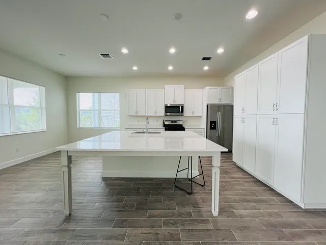 a kitchen with stainless steel appliances a table and chairs in it