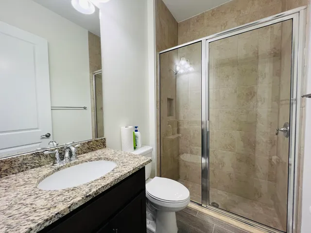 a bathroom with a granite countertop sink toilet and shower