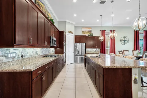 a kitchen with stainless steel appliances granite countertop a sink dishwasher a refrigerator and wooden cabinets with wooden floor