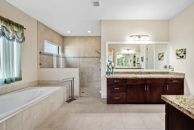 a spacious bathroom with a granite countertop tub sink and mirror