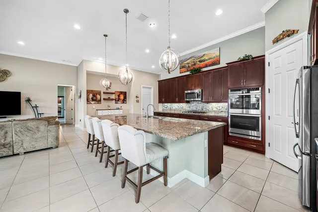 a kitchen with stainless steel appliances kitchen island granite countertop a refrigerator and a stove top oven