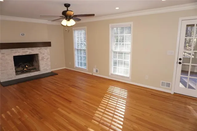 a view of an empty room with wooden floor fireplace and a window
