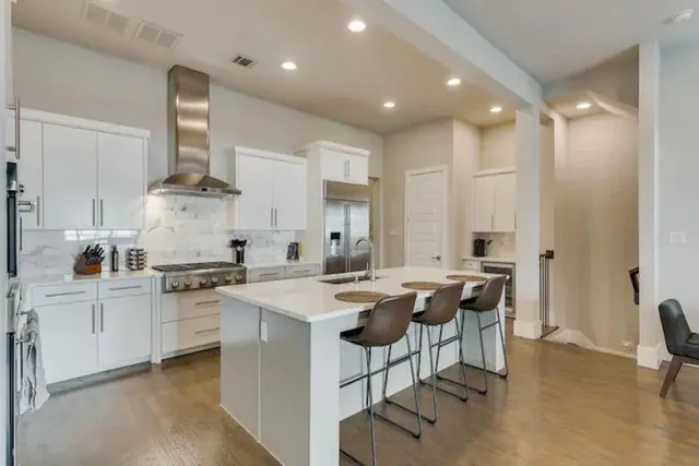 a kitchen with appliances a sink a stove a dining table and chairs