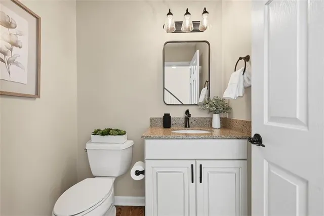 a bathroom with a granite countertop toilet sink and mirror