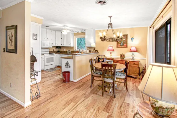 a dining room with wooden floor a chandelier a wooden table and chairs
