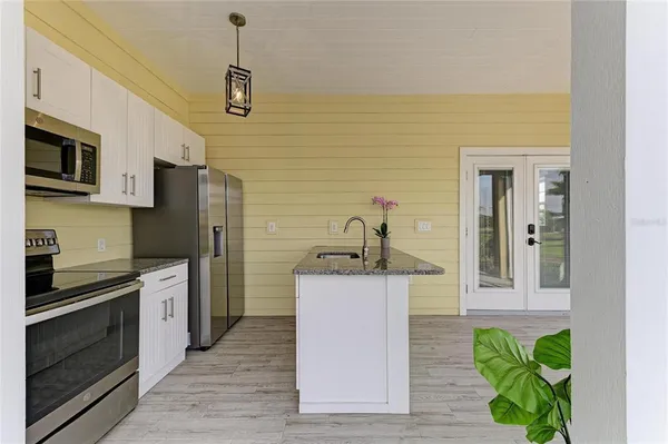 a view of a kitchen with kitchen island a counter top space a sink and cabinets